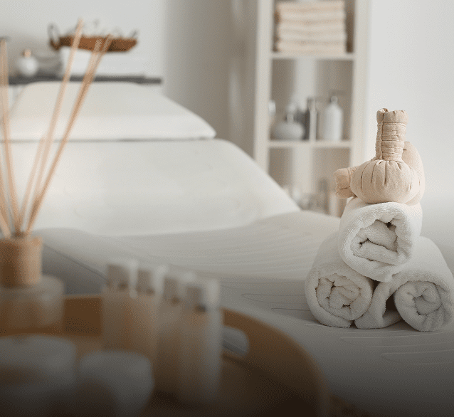 Cozy spa setup with towels and essential oils on a treatment bed.